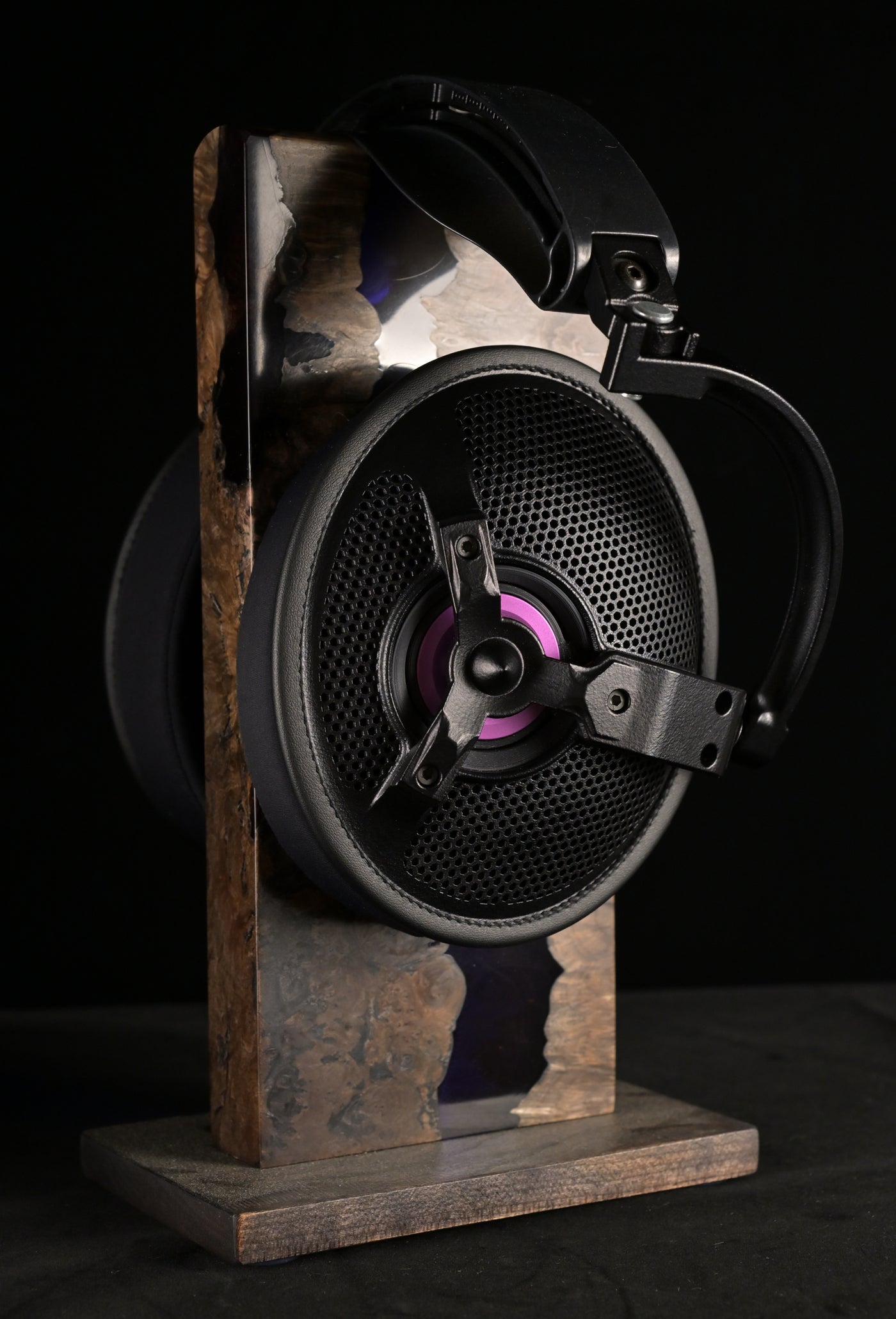 ETA ULI AlNiCo open-back headphone on a burl wood and resin stand, side profile showing the circular open-back grille, three-spoke driver chassis and purple voice coil