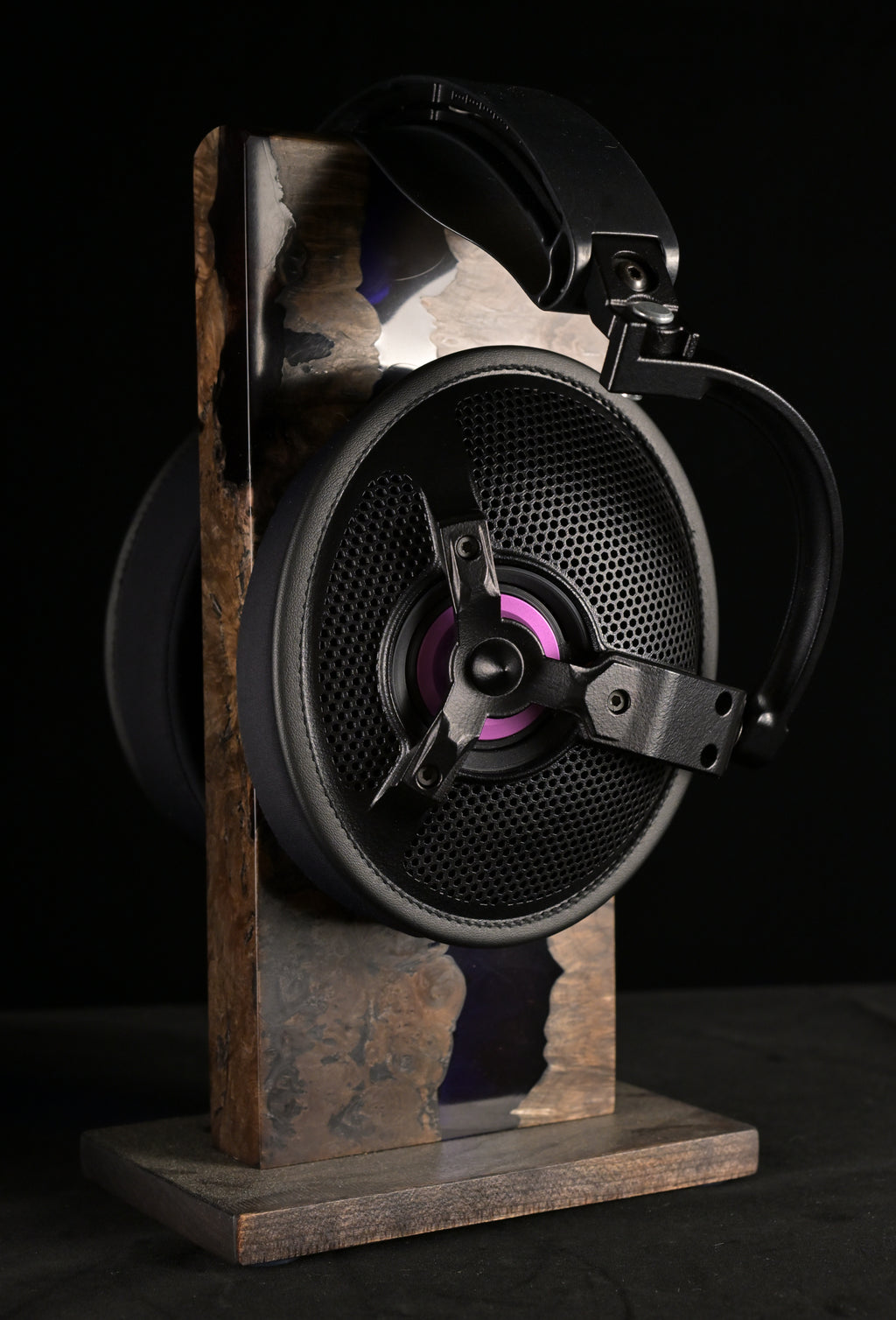 ETA ULI AlNiCo open-back headphone on a burl wood and resin stand, side profile showing the circular open-back grille, three-spoke driver chassis and purple voice coil