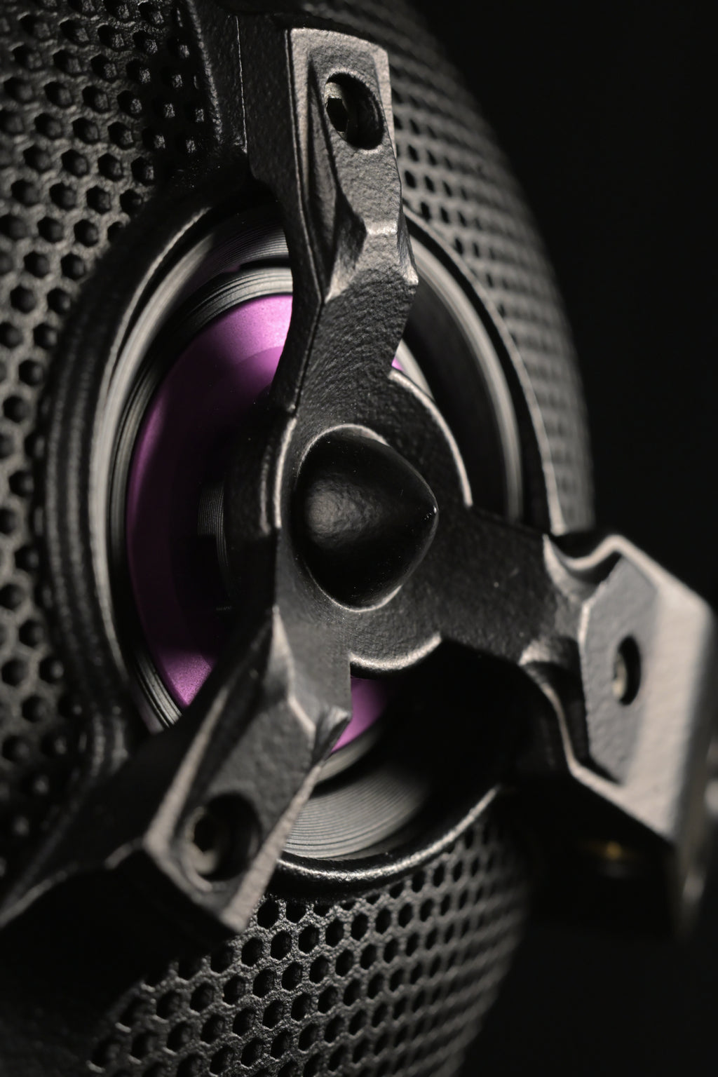 Macro close-up of the ETA ULI open-back driver showing the perforated black grille, three-spoke chassis bracket and purple AlNiCo voice coil