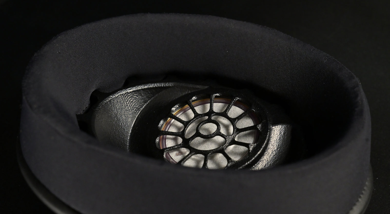ETA ULI earcup viewed from the side, black suede earpad around the 3D-printed driver baffle with floral spoke pattern and magnet