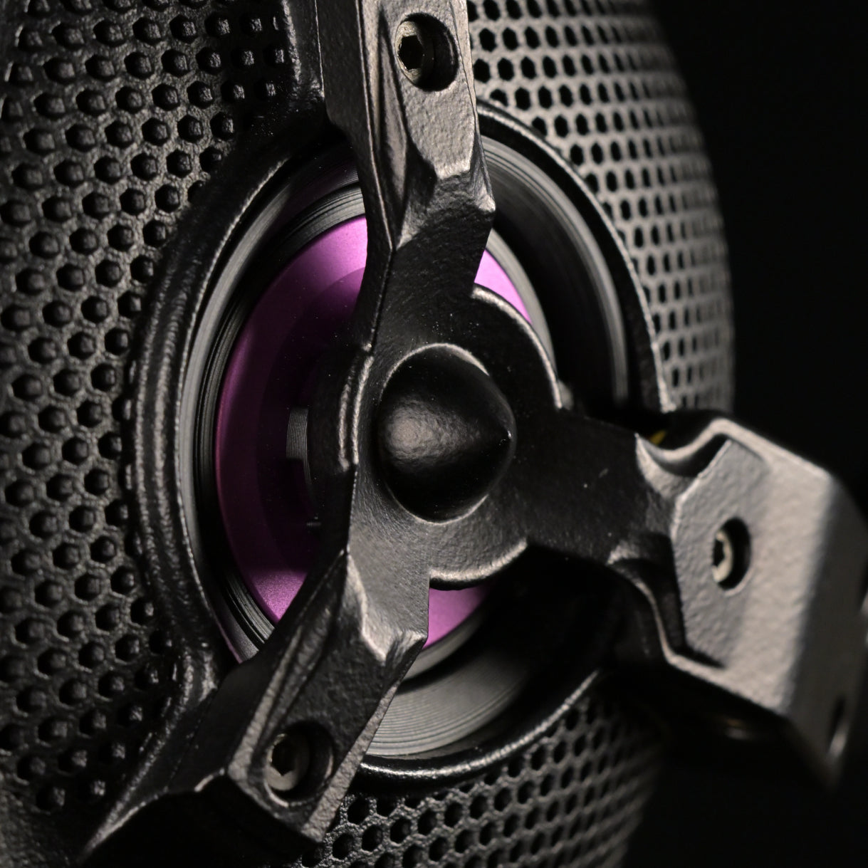 Macro detail of the ETA ULI open-back driver showing the perforated grille, three-spoke chassis and purple AlNiCo voice coil